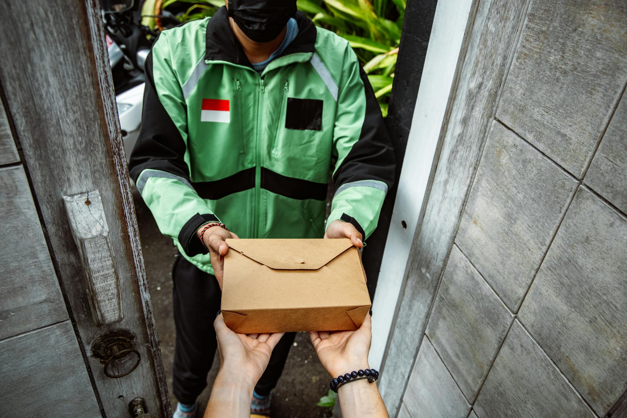 Courier delivers a package to a customer's doorway, showcasing a personal hand-off moment.